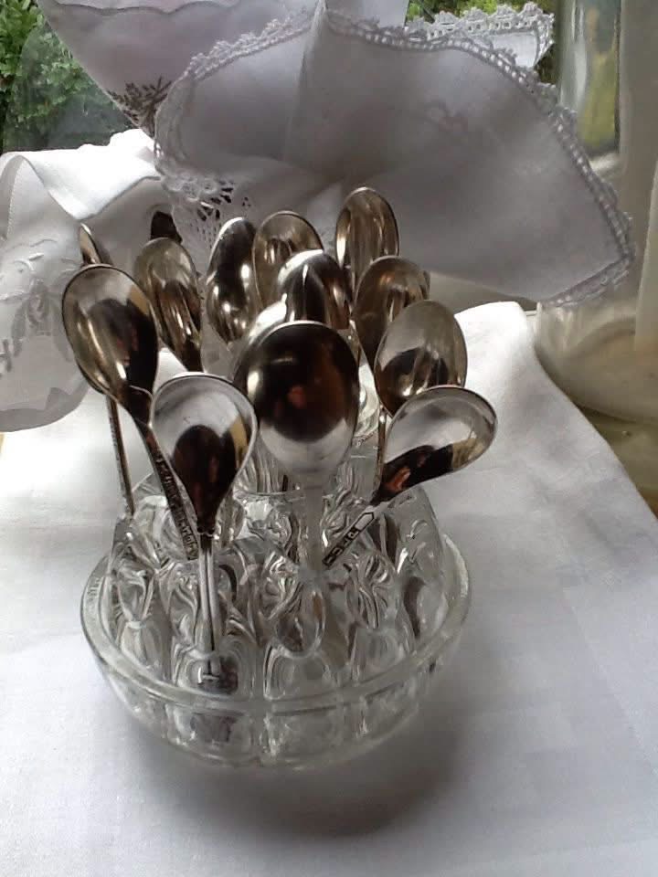 Silver teaspoons displayed in a clear glass flower frog