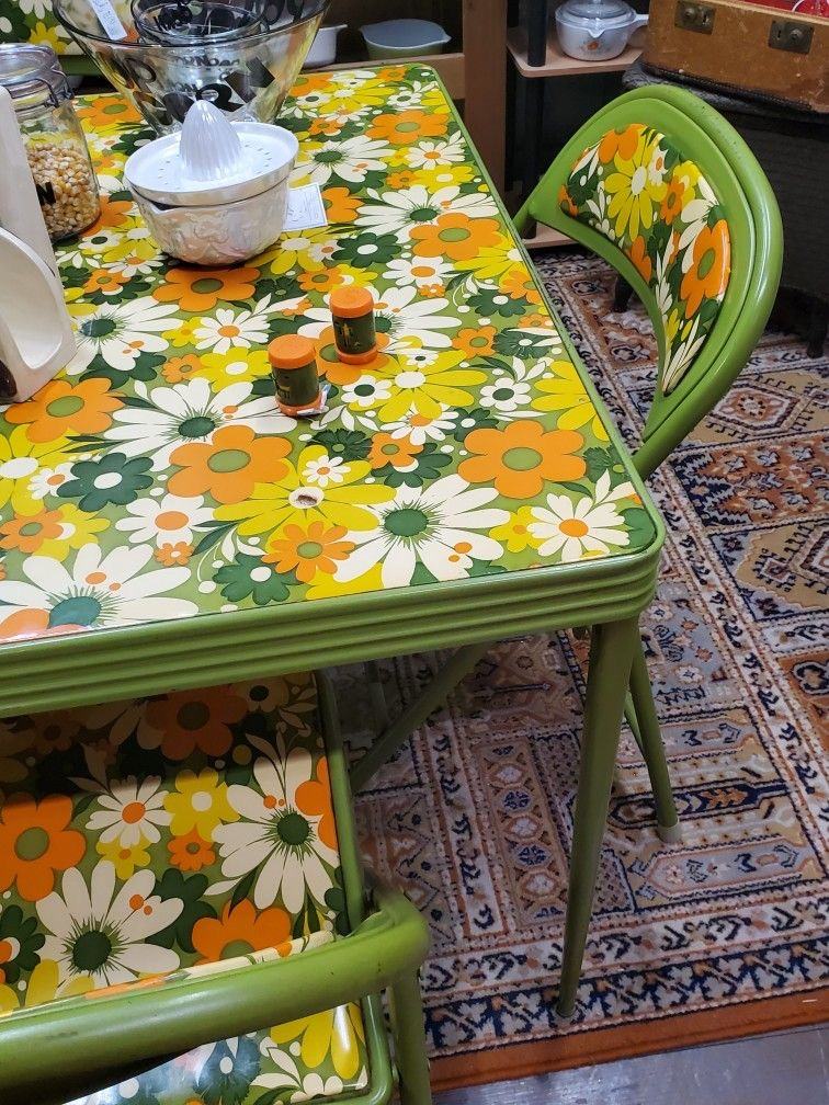 Green dining table and chairs with yellow and white floral surfaces