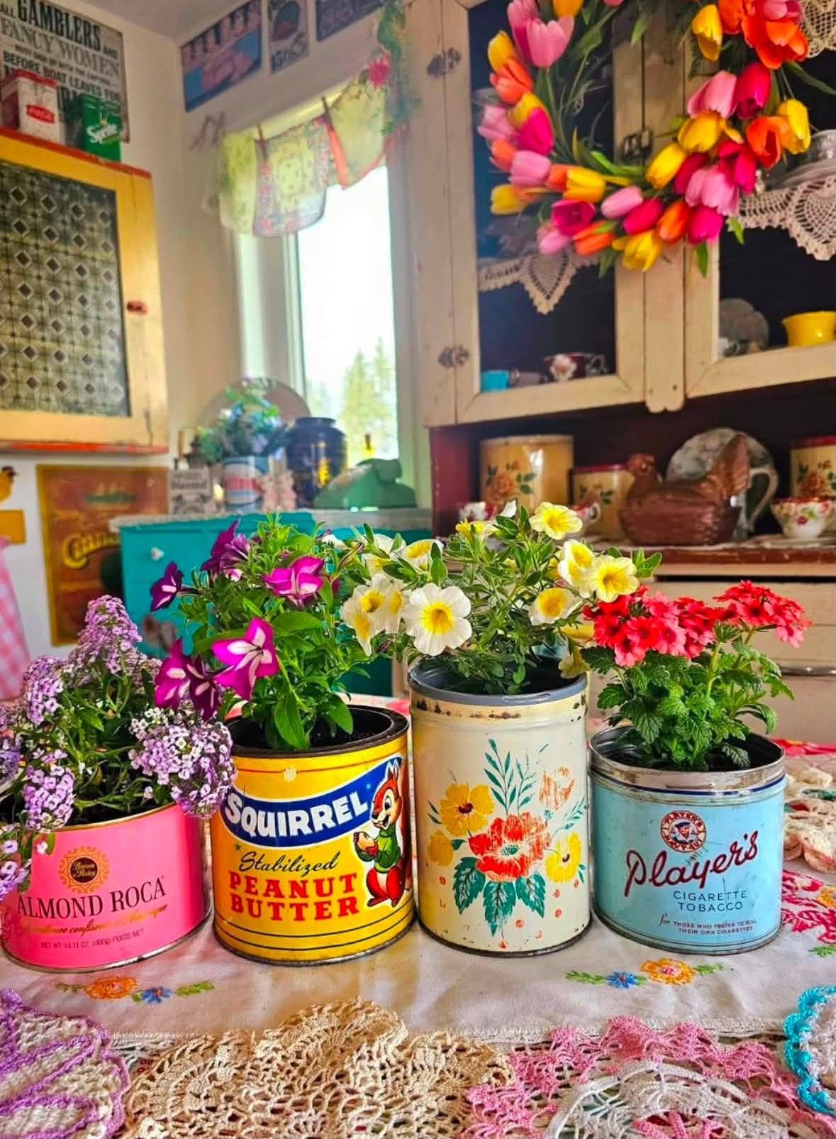 Flowers in colorful vintage tins on a kitchen table