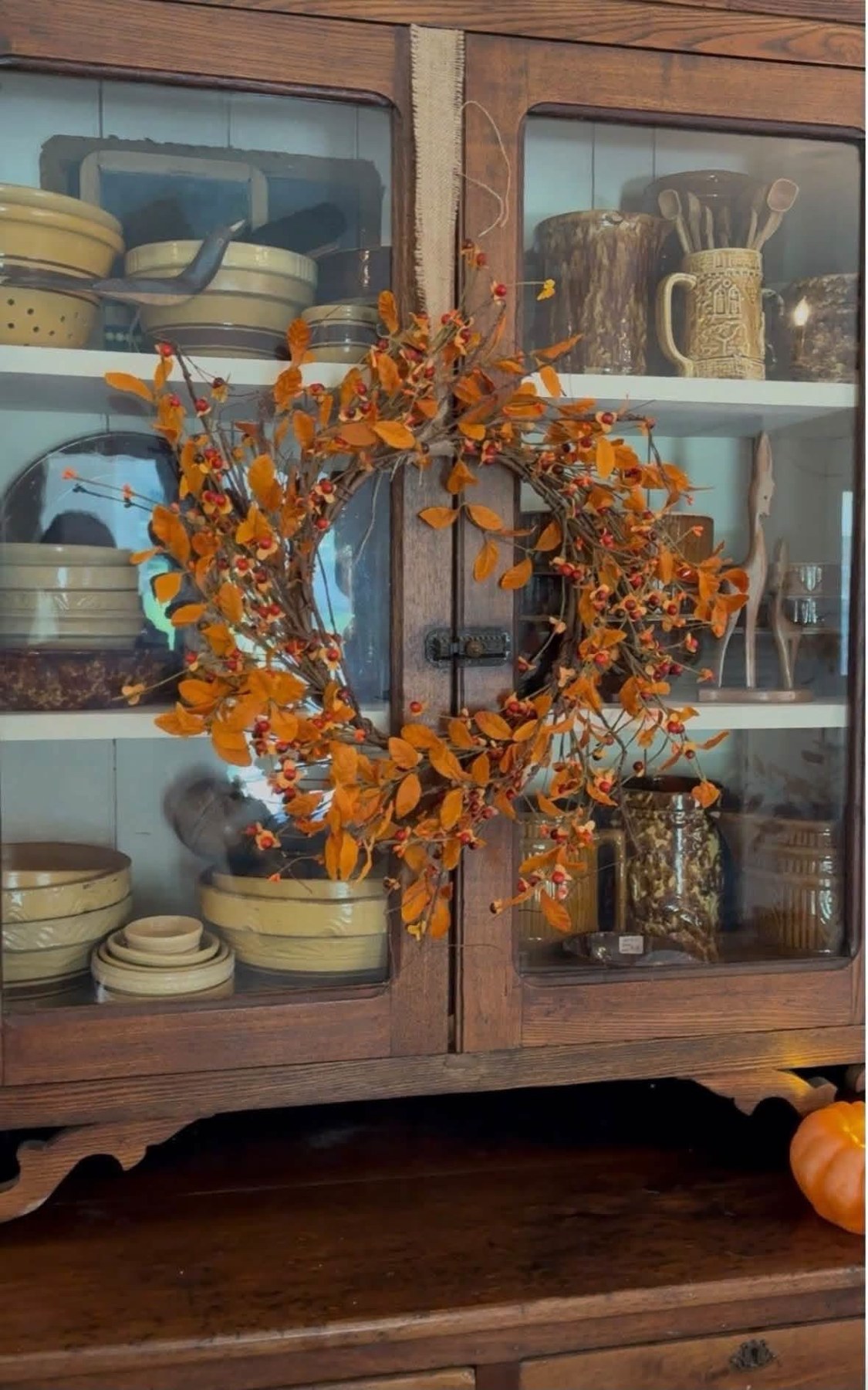 Autumn wreath hanging on a vintage dish cabinet