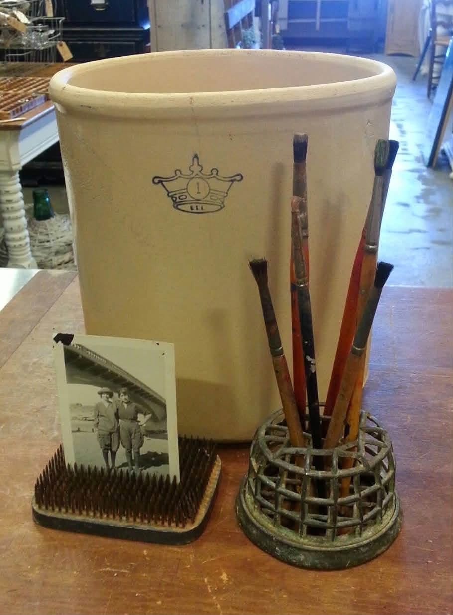 Flower frogs holding paintbrushes and a vintage photograph beside a crock